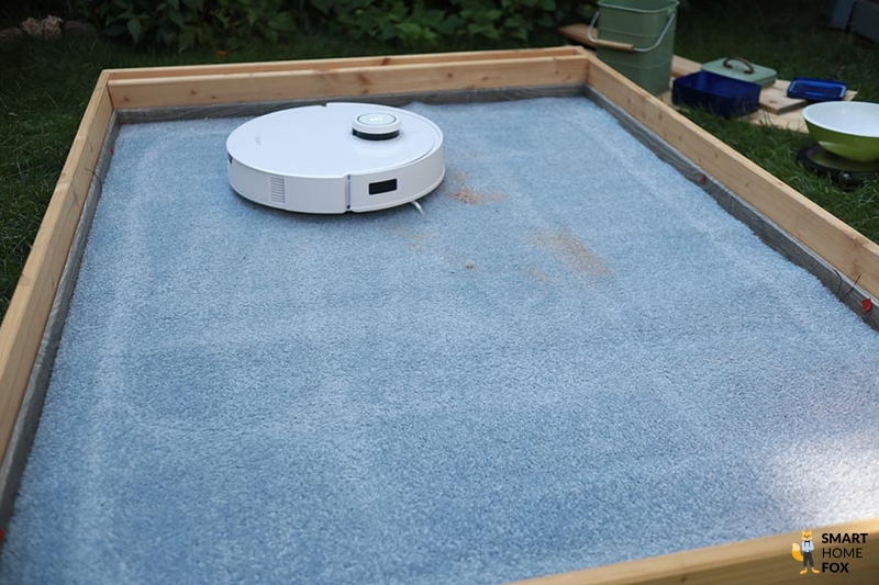 Ecovacs Deebot T10 reinigt Sand auf einem Teppich im Saugtest.